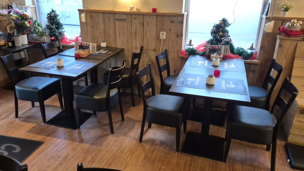 Het mini-restaurant van Cafetaria Oud Waubach, met tafels en placemats met het logo van de zaak.